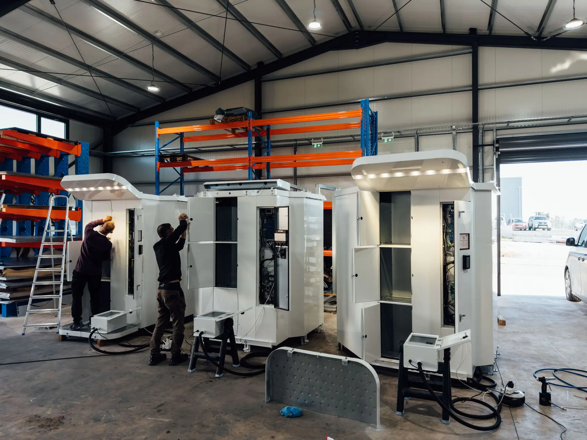 טכנאים מרכיבים מכונות GasAutomat במפעל של VendingRobotics בפאפוס. גגוני ה-LED דולקים.